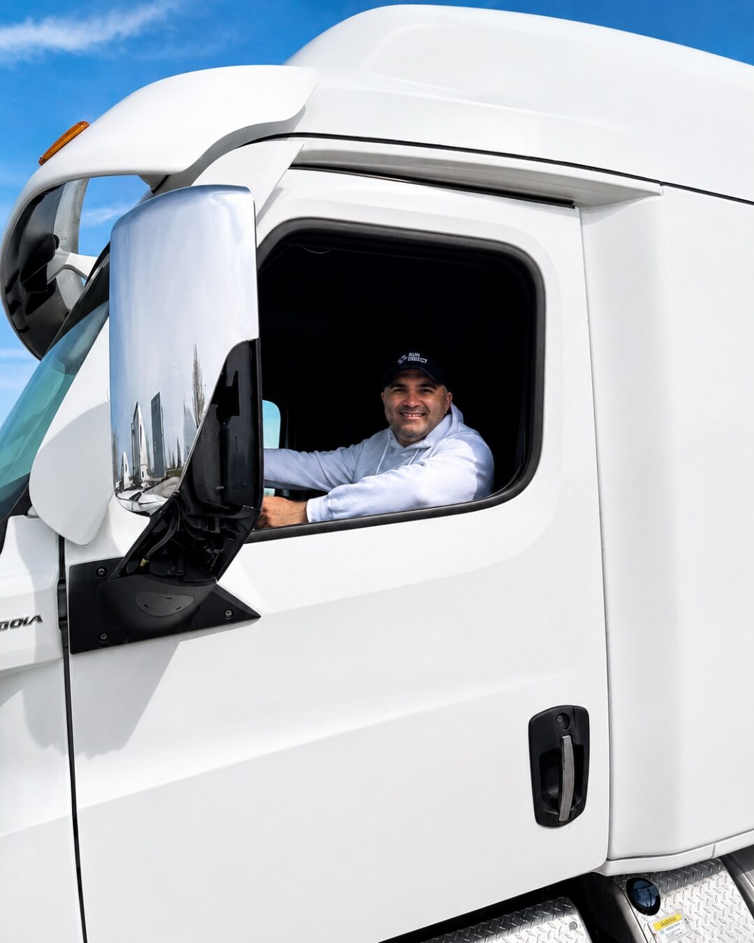 Driver in the window of a 2024 Freightliner Cascadia cab