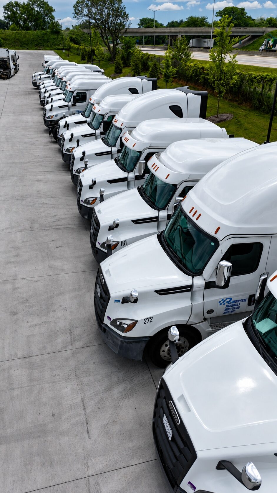 A row of Run Direct Freightliner Cascadia trucks parked in the yard